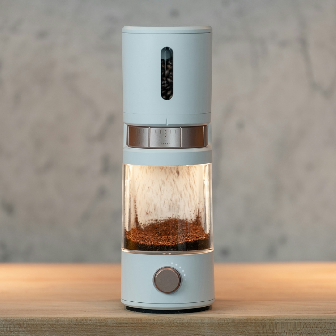 A sleek smart coffee grinder with copper accents from Voltaire is grinding a fresh batch of coffee beans.
